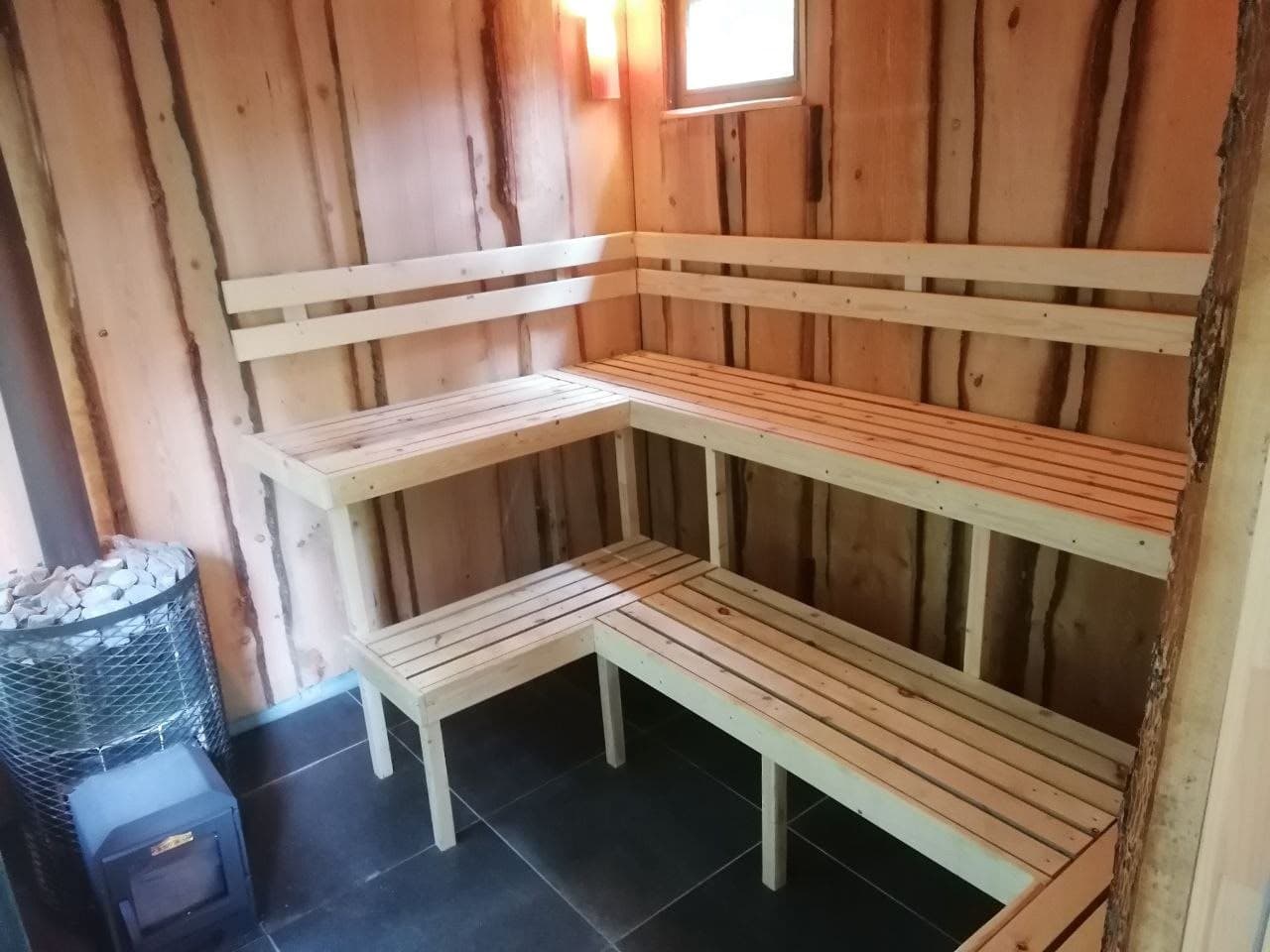 Innenraum der Holzsauna mit Sitzbänken und Saunaofen